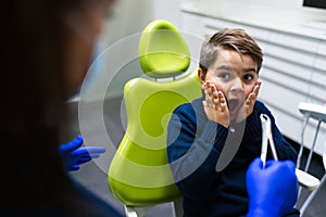 Boy scared of dentist with forceps. Ð¡hild is afraid to remove tooth. Teen refuses to treat teeth.