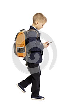 Boy in school uniform with a backpack looks into the phone, isolated on white background