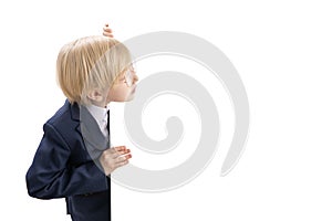 Boy in school uniform peeks out from white board. Schoolboy in isolation on white background. Place for your text. Copy space