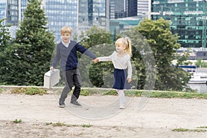 A boy in a school uniform with a small schoolbag pulls a beautiful blonde girl by the hand