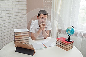 A boy schoolboy does his homework. Textbooks and notebooks on the table