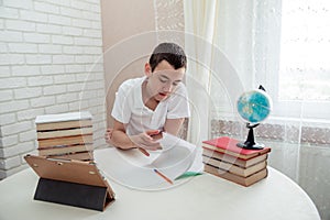 A boy schoolboy does his homework. Textbooks and notebooks on the table