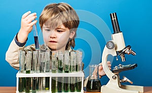 Boy scientist in laboratory. Cute kid making science experiment. Little child with test tubes and microscope. Education.