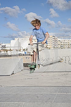 Boy with scooter is jumping at the skate park