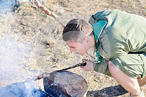 Boy Scout Cooking Sausages Over Campfire