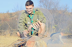 Boy Scout Cooking Sausages on Stick over Campfire