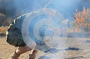 Boy Scout Cooking Sausages on Sticks over Campfire