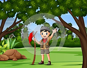 A boy scout holding a flag walking in forest