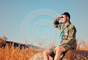 Boy Scout Sitting on Rock Watching Over the Field