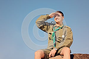 Boy Scout Sitting on Rock Watching Over the Field