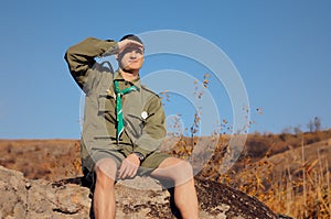 Boy Scout Sitting on Rock Watching Over the Field