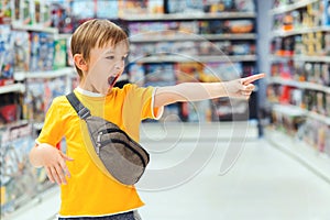 Boy screams and demands a toy in the store. Little boy getting hysterical in toy shop. Ð¡hildren`s tantrum in the store