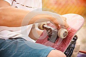 Boy screws the truck on the skateboard After sticker griptape