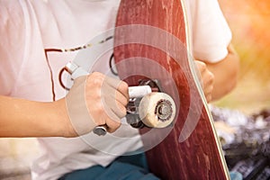 Boy screws the truck on the skateboard After sticker griptape