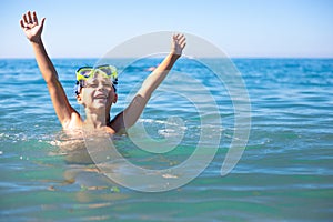 A boy with scuba diving glasses in the sea enjoys the summer sun, vacation and fun swimming
