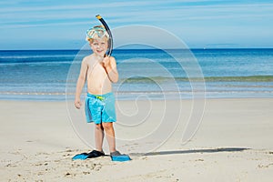 Boy in scuba mask with fins stand on the beach ready to dive