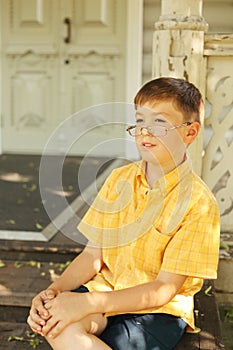 Boy seat on stairs of wooden house