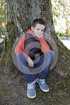 Boy seated against a tree