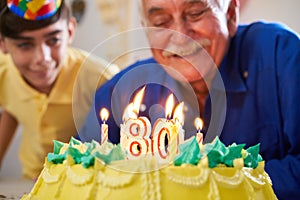 Boy and Senior Man Blowing Candles On Cake Birthday Party