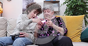 Boy and senior women playing video game on console. Grandmother and grandson playing video games using gamepads at home