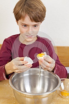 Boy separating egg white from egg yolk photo