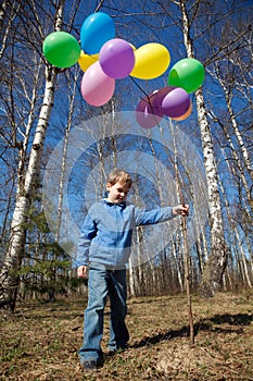 Boy with sheaf of balloons in park in spring