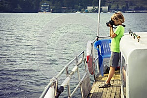 Boy on the ship photographing water