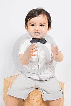 boy in a shirt and bow tie sit on box ready to applaud