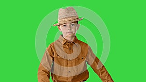 Boy in a shirt and straw hat walking waving his hands and looking at camera on a Green Screen, Chroma Key.