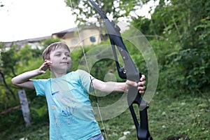 Boy shooting bow in park
