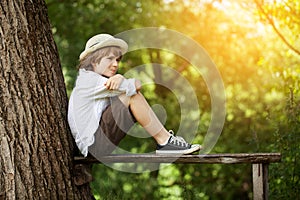 Boy in shorts and a hat sits