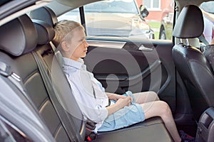 Cute sad boy sitting in a car wearing a seat belt