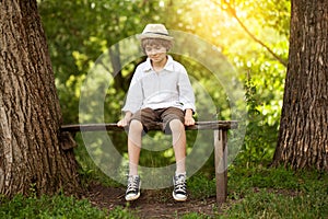 Boy in shorts sits on a bench