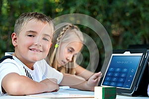 Boy showing homework on tablet outdoors.