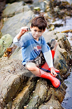 Boy showing snail by rockpool