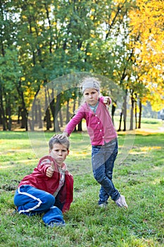 Boy showing thumb up and girl thump down in autumn park