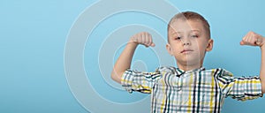 The boy shows his strength. a boy in a plaid shirt on a blue background. concept of physical development of children.