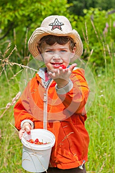 The boy shows the strawberry