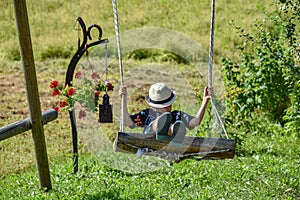 The boy shuts in a wooden swing in nature