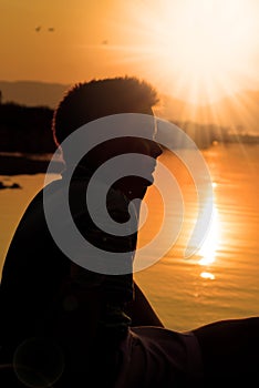 Boy silhouette, sunset at lake