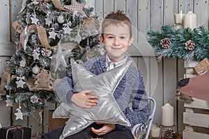 Boy with silver star sitting on sledge under Christmas tree