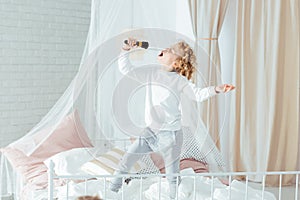 Boy singing, standing on bed