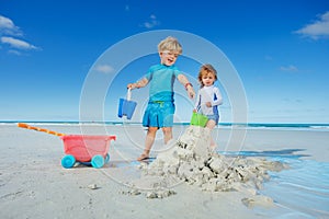 Boy and sister girl play with sand, water at the ocean beach