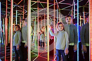 Boy and sister wander in semidarkness of mirror labyrinth