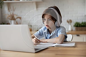 Boy sit at table studying at home online use laptop