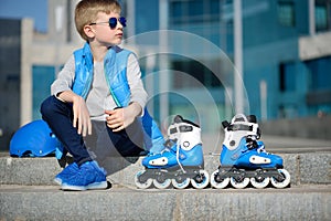 Boy siting with inline roller skates at outdoor skate park