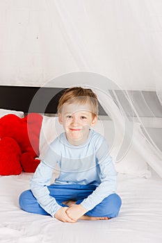 Boy sits on a bed in a comfortable situation