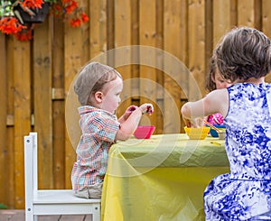 Boy Sits Dyeing Easter Eggs Together with Children