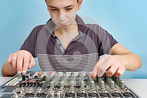 The boy sits at the mixing console and adjusts the sound with fenders