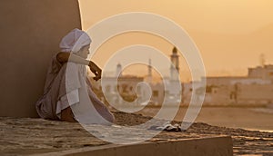 Boy sits next to a wall watching the sunset